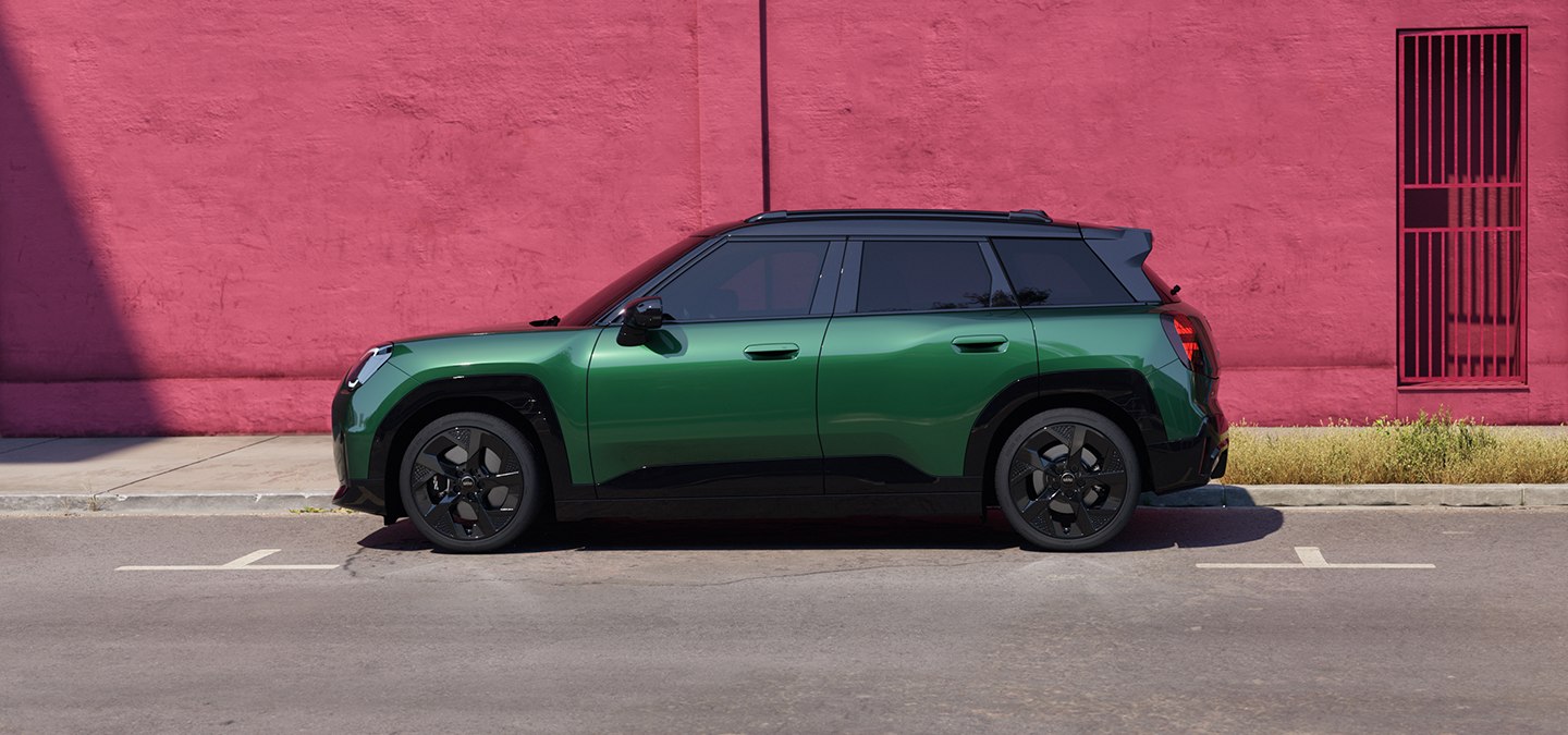 Bočný pohľad na čisto elektrické MINI Aceman vo farbe British Racing Green so strechou Black na ulici.