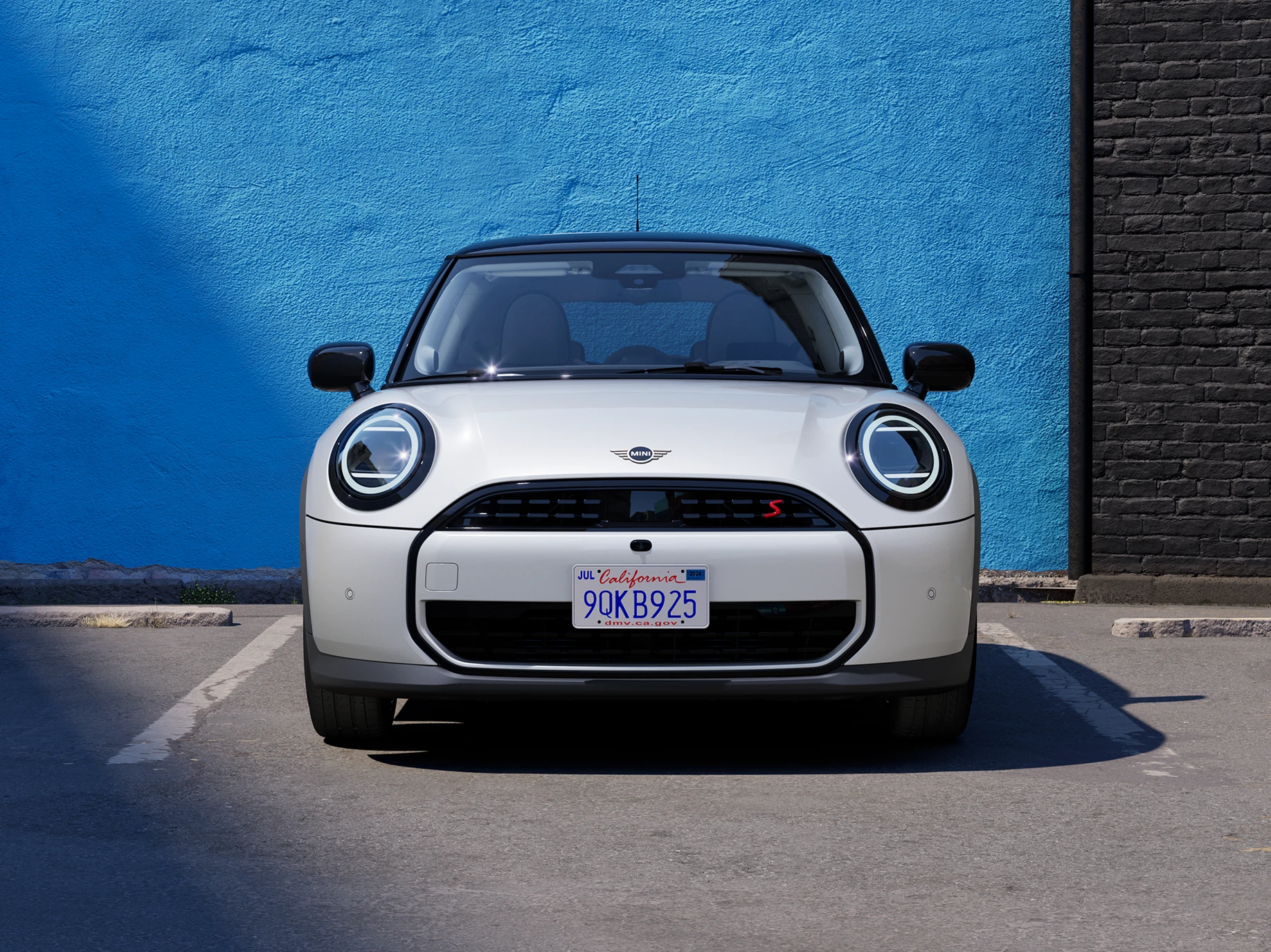 Pohľad spredu na MINI Cooper vo farbe Nanuq White so strechou Black na parkovisku.