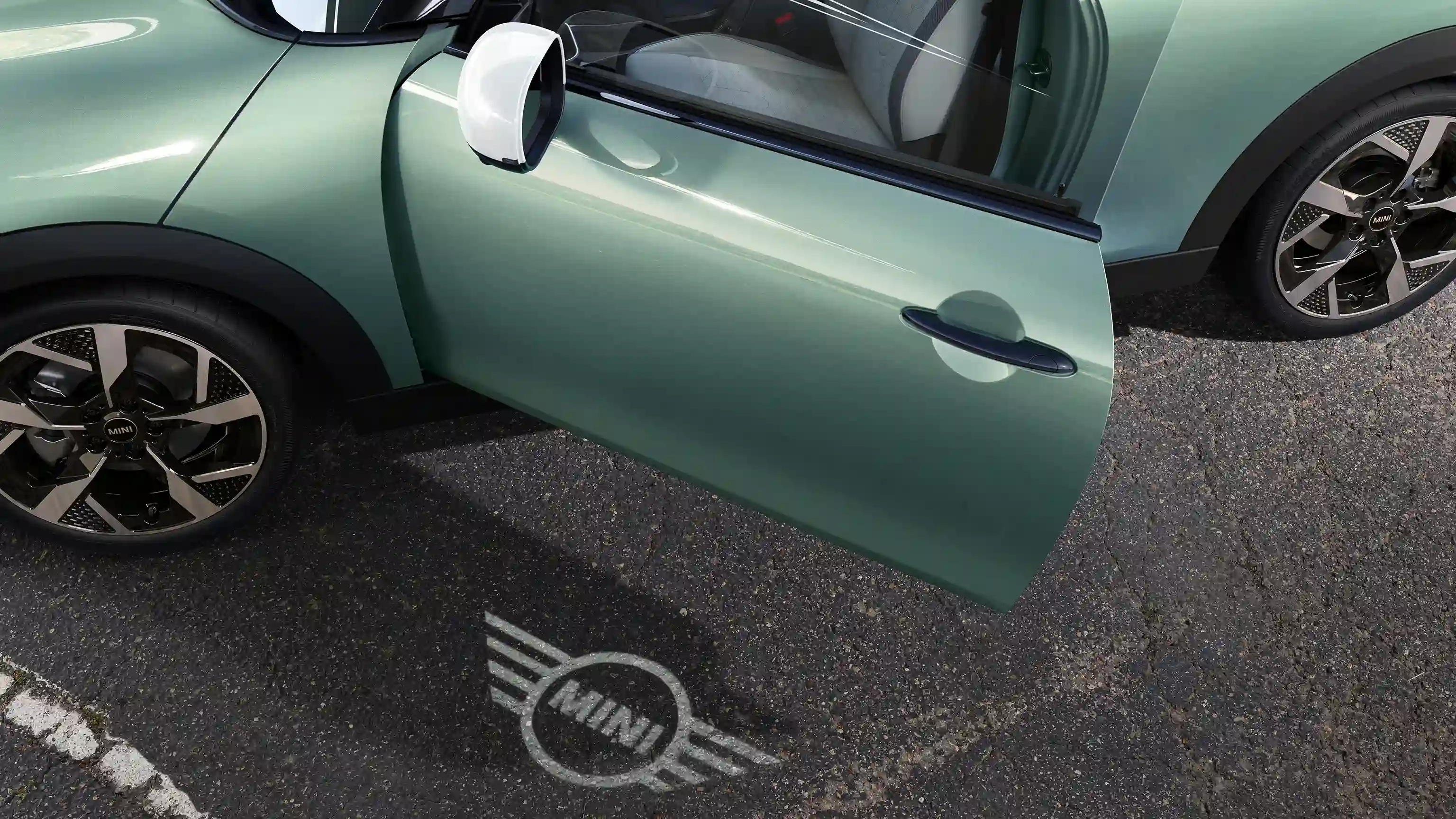 Pohľad na exteriér MINI Cooper s otvorenými dverami a uvítacím svetlom s logom MINI na zemi 