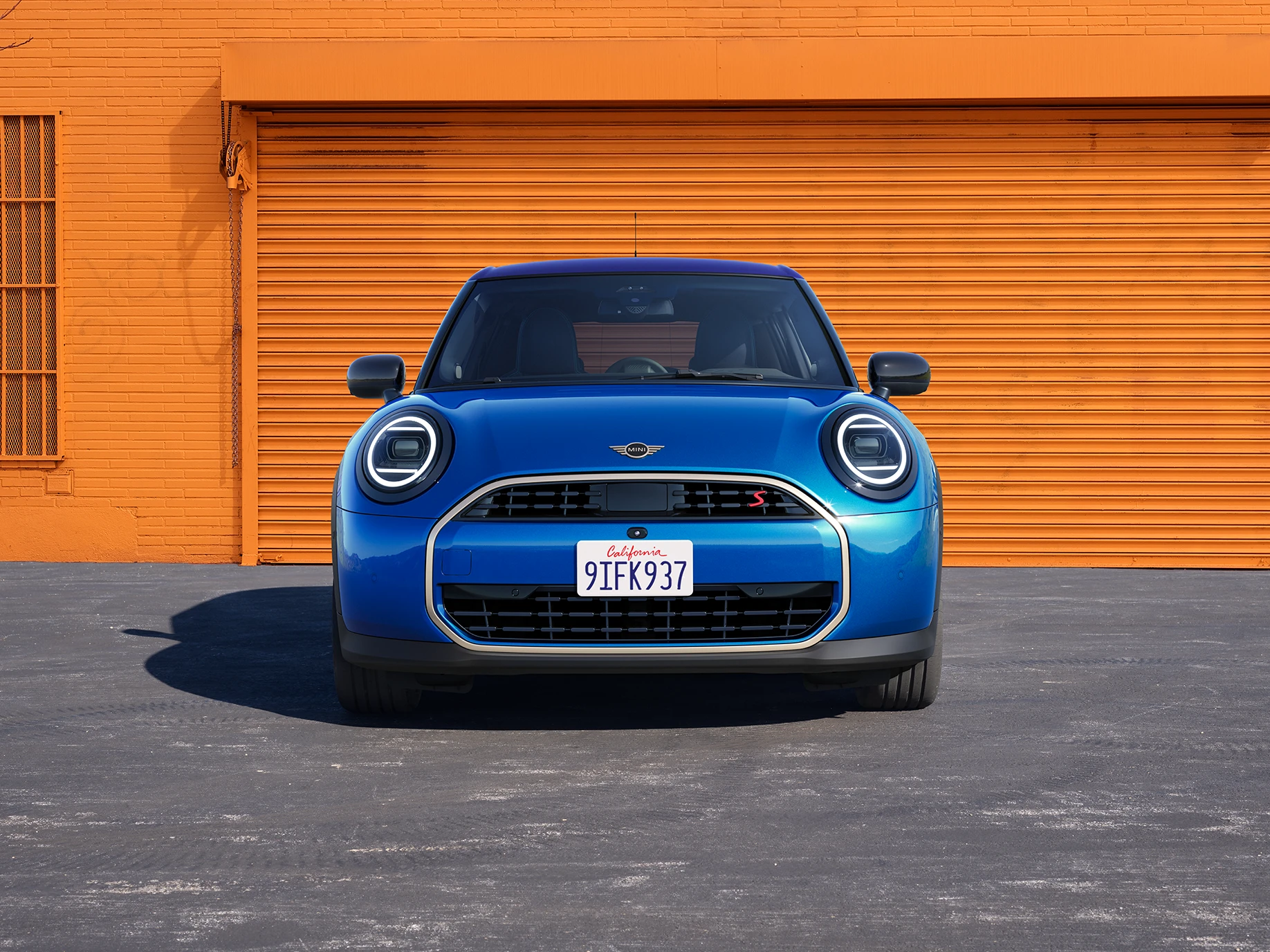 Pohľad spredu na MINI Cooper 5-dverové vo farbe Icy Sunshine Blue s viacfarebnou strechou Multitone Blue.