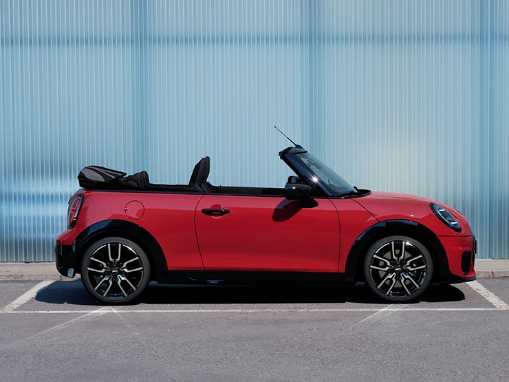 Bočný pohľad na MINI Cooper Cabrio vo farbe Chili Red na ulici.