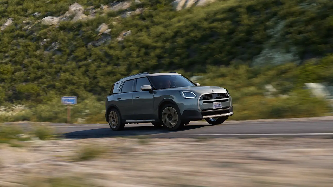 Pohľad na MINI Countryman vo farbe Smokey Green v štýle Favoured počas jazdy v teréne