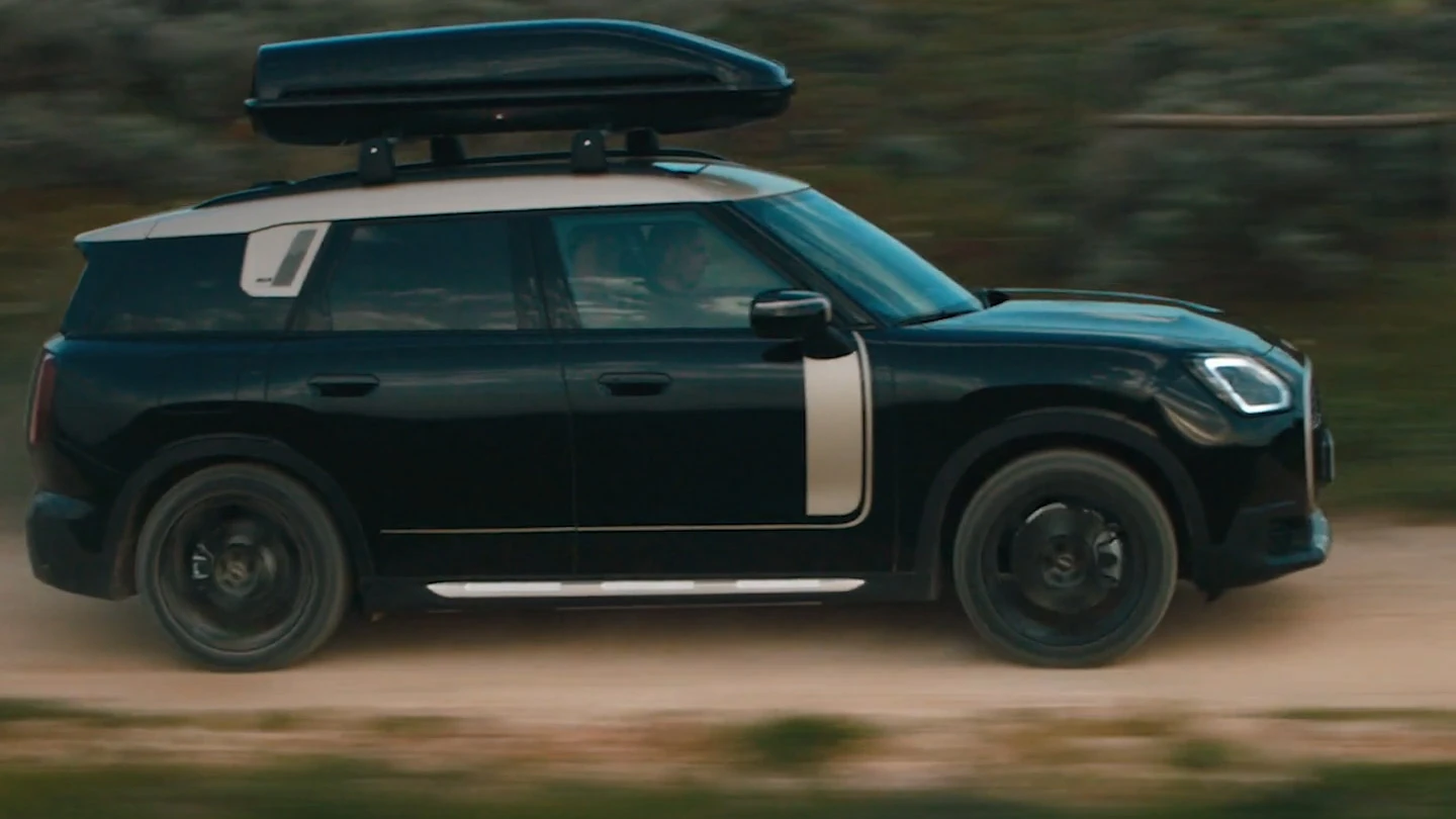 MINI Countryman v metalíze Midnight Black s 19-palcovými kolesami John Cooper Works Runway Spoke v čiernej farbe počas jazdy v teréne. 