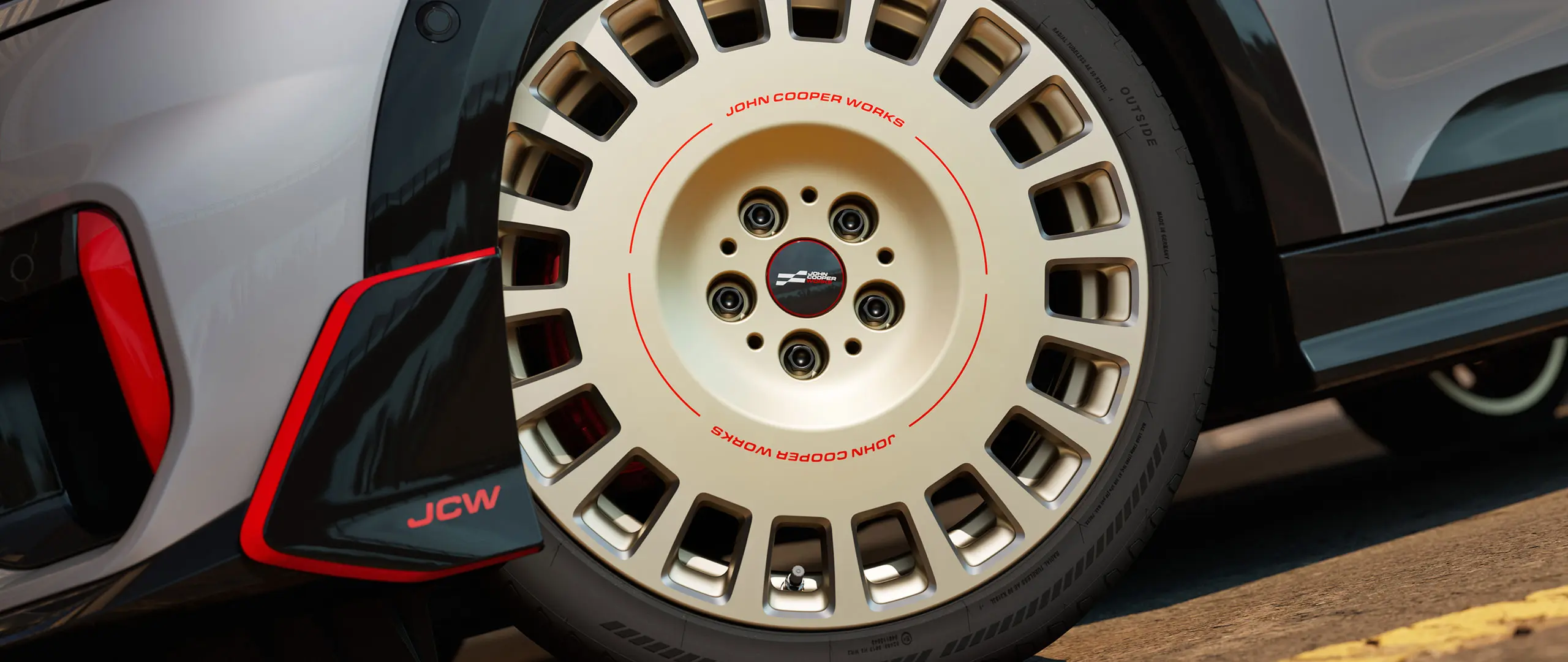 Detailný záber 18-palcového kolesa JCW Rallye Spoke 964 vo dvojfarebnom vyhotovení Vibrant Silver/diamantové frézovanie a predné krídlo.