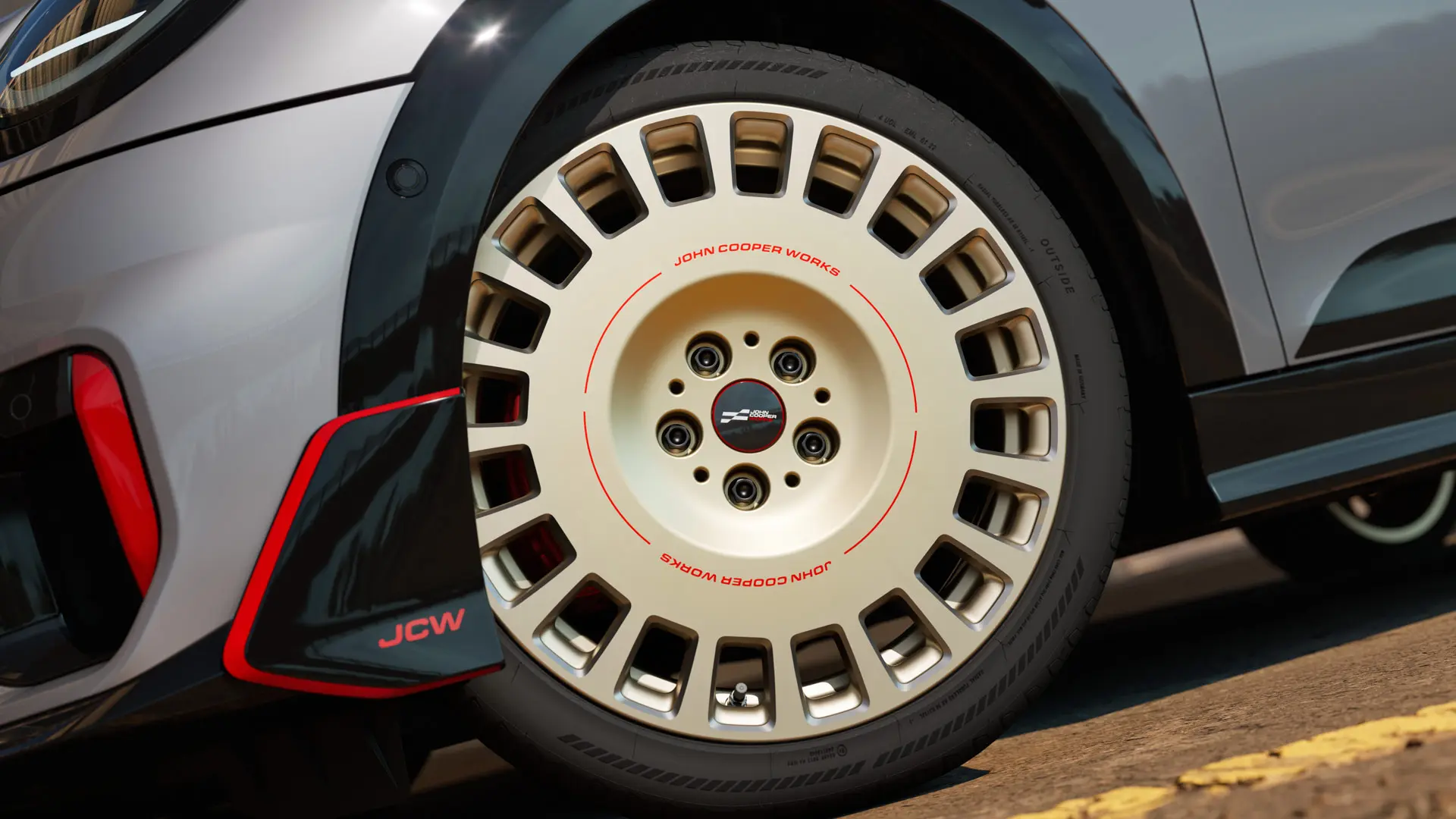 Detailný záber 18-palcového kolesa JCW Rallye Spoke 964 vo dvojfarebnom vyhotovení Vibrant Silver/diamantové frézovanie a predné krídlo.