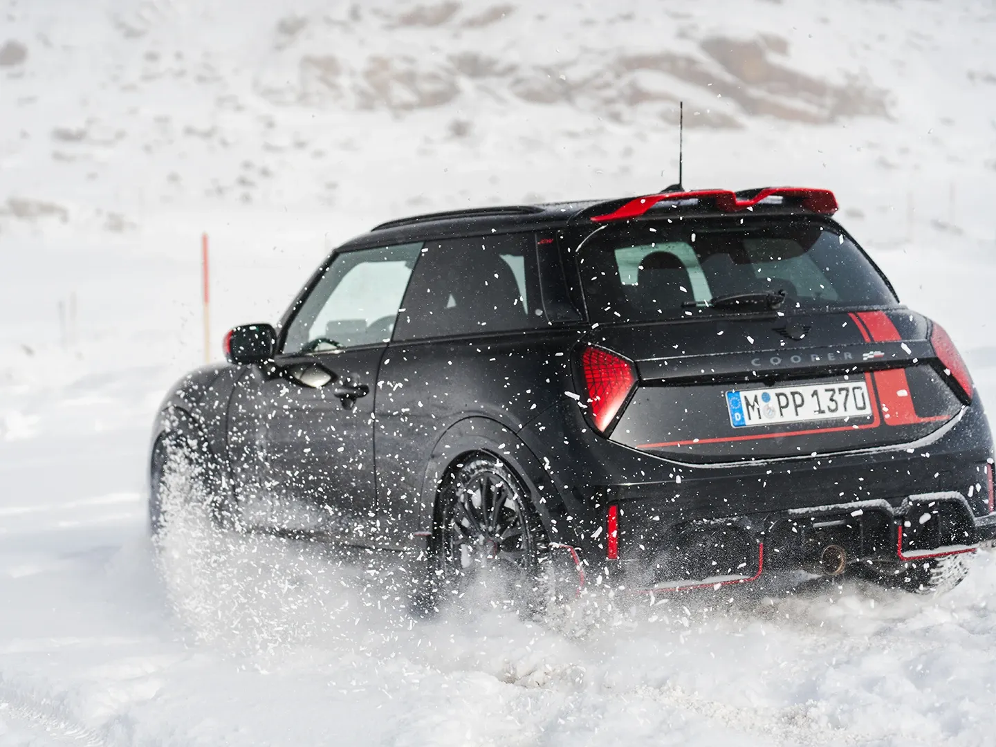 Zadný pohľad na MINI Cooper JCW počas jazdy na snehu.