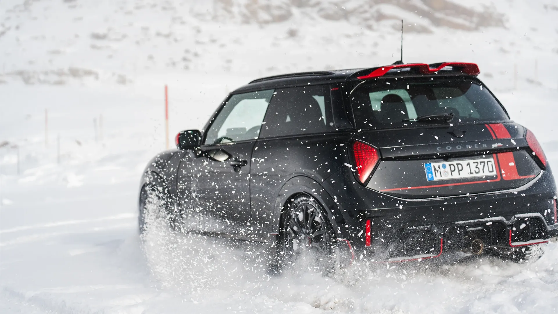 Zadný pohľad na MINI Cooper JCW počas jazdy na snehu.