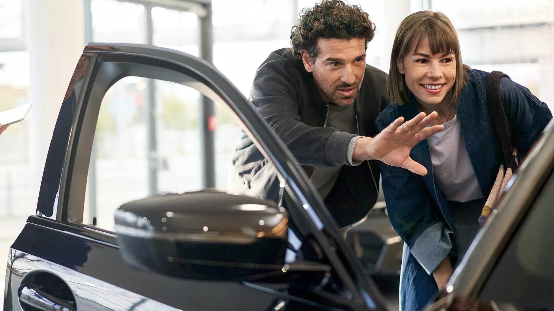 MINI v priestoroch predajcu MINI, s konzultantom, ktorý vysvetľuje zákazníkovi interiérové funkcie.