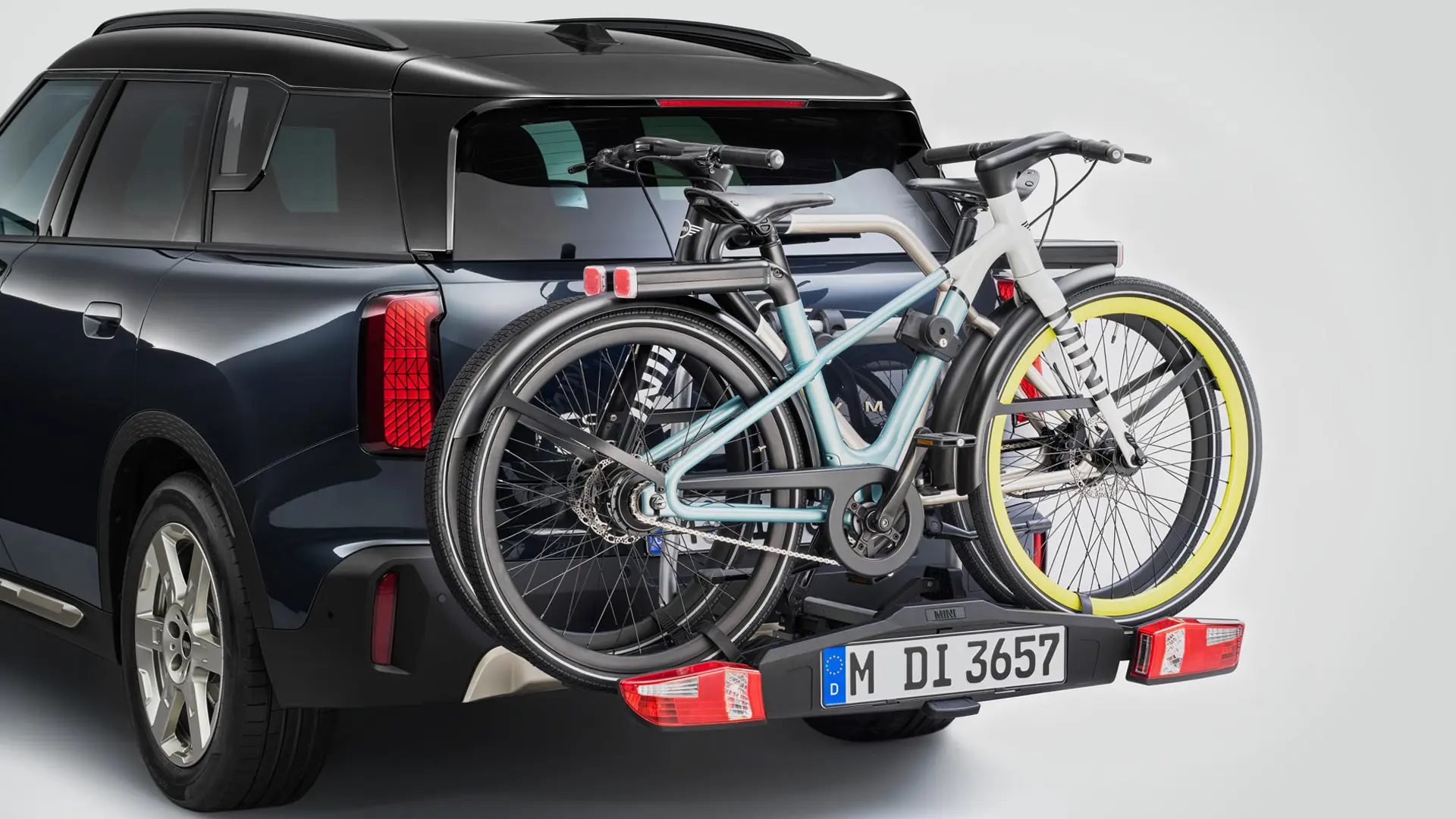 MINI Countryman v čiernej farbe so zadným nosičom bicyklov a dvoma pripevnenými horskými bicyklami, zadný pohľad.
