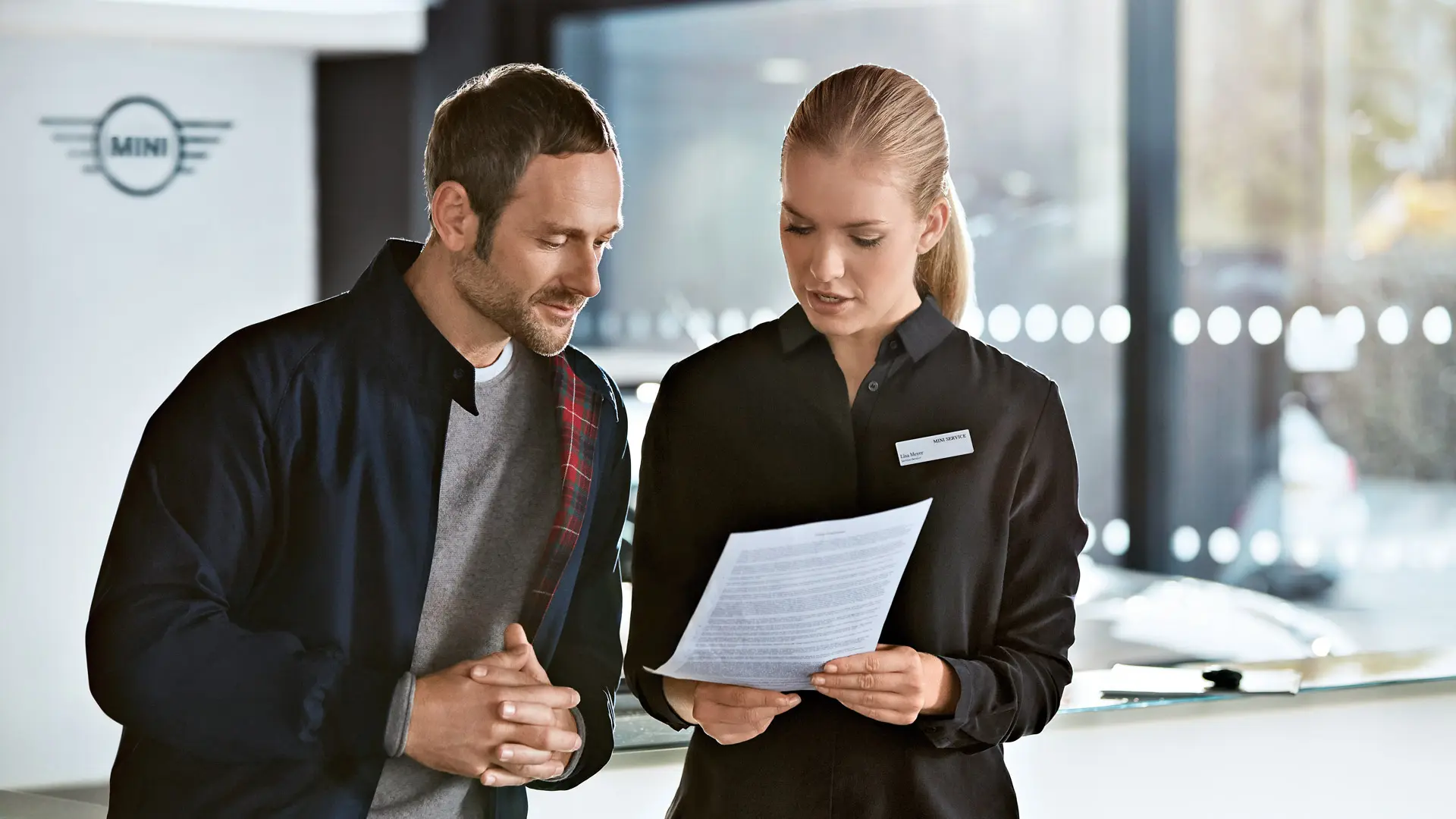 Servisný poradca MINI poskytujúci poradenstvo zákazníkovi o servisných plánoch v centre MINI.