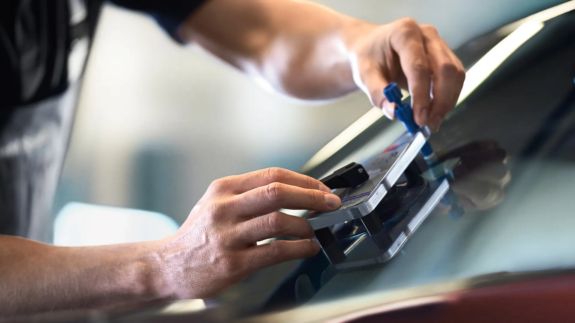 Pracovník MINI opravujúci čelné sklo