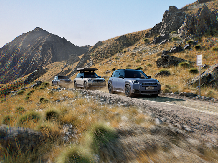 Obrázok viacerých modelov MINI Countryman Untamed Edition počas jazdy na terénnej horskej ceste.
