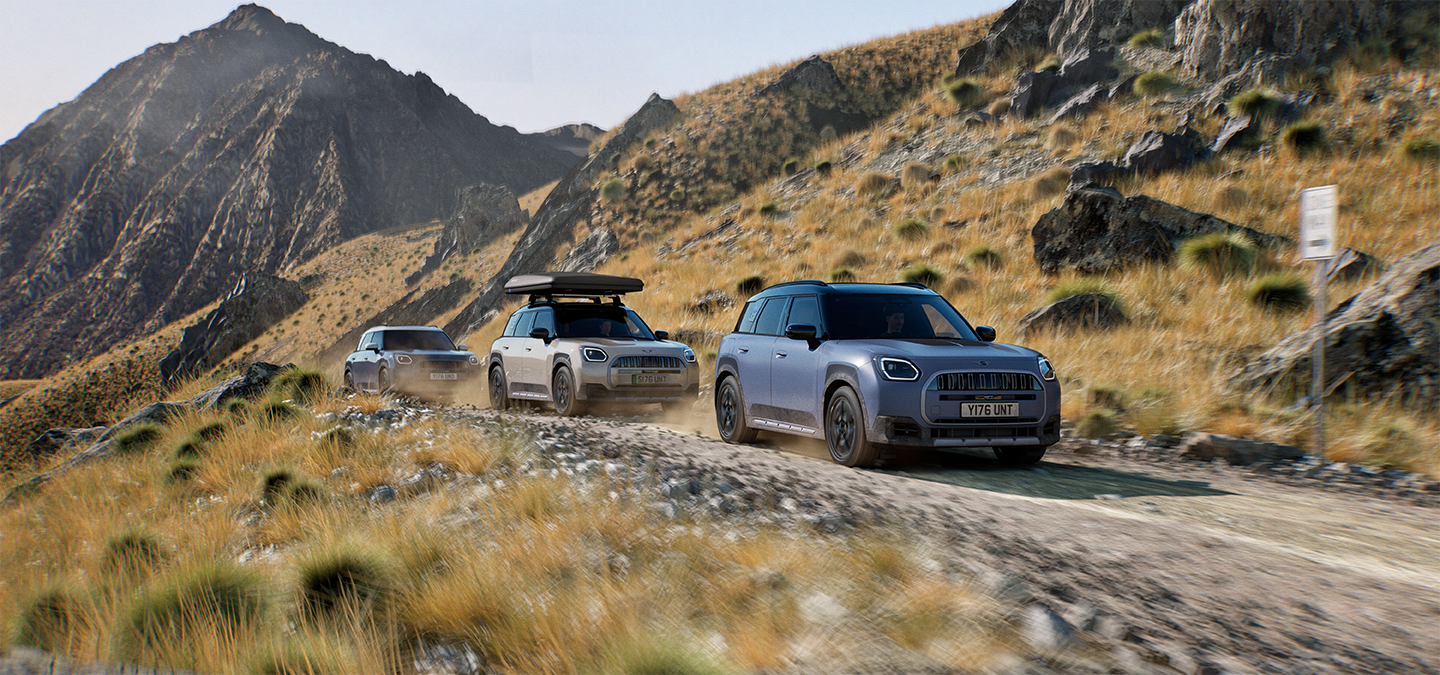 Obrázok viacerých modelov MINI Countryman Untamed Edition počas jazdy na terénnej horskej ceste.
