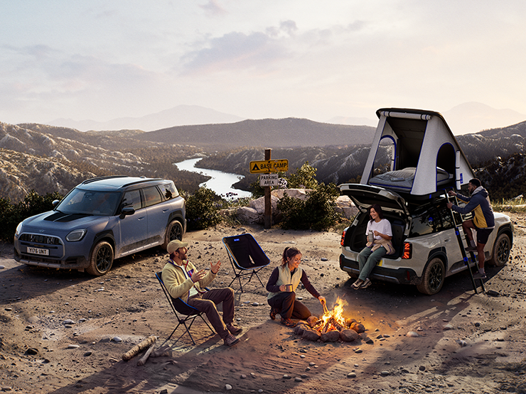 Obrázok dvoch vozidiel MINI Countryman Untamed Edition na vrchole hory pri západe slnka.