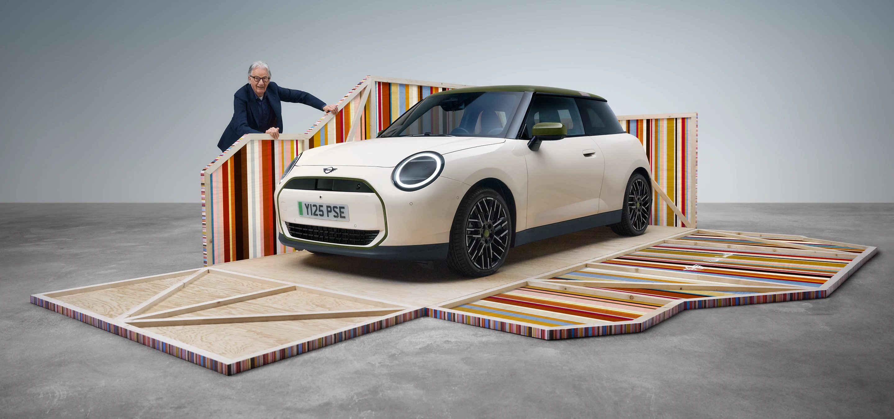 Predný pohľad na čisto elektrické MINI Cooper Paul Smith Edition vo farbe Inspired White s dizajnérom Paulom Smithom